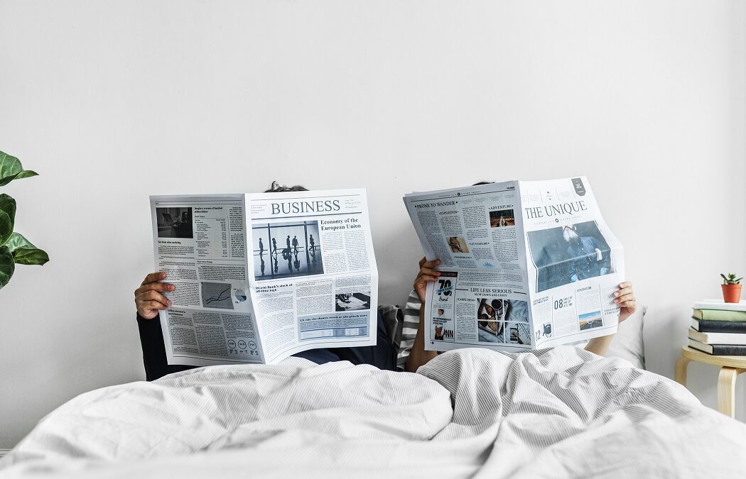 Asian couple reading newspapers in bed